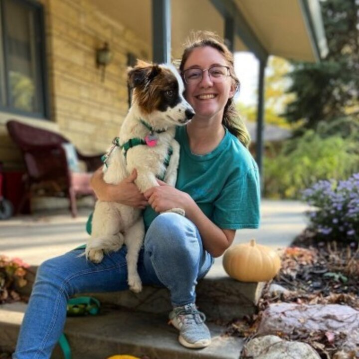 Emily Schumacher sits on a step outside her house, holding her dog, Lady.